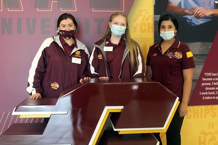 Central Michigan University Admissions staff members Skyler Conran (left), Bridget LaPoint, and Patricia Young (right), show off their game day buttons in the Bovee University Center at CMU.